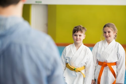 A brother and sister wait patiently for their martial arts class to start.