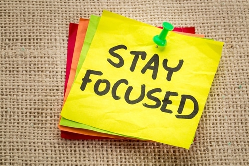 A stack of Post-It notes displays "Stay Focused" on the top of the stack.