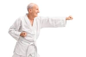 An elderly man smiles joyfully as he begins his martial arts training.