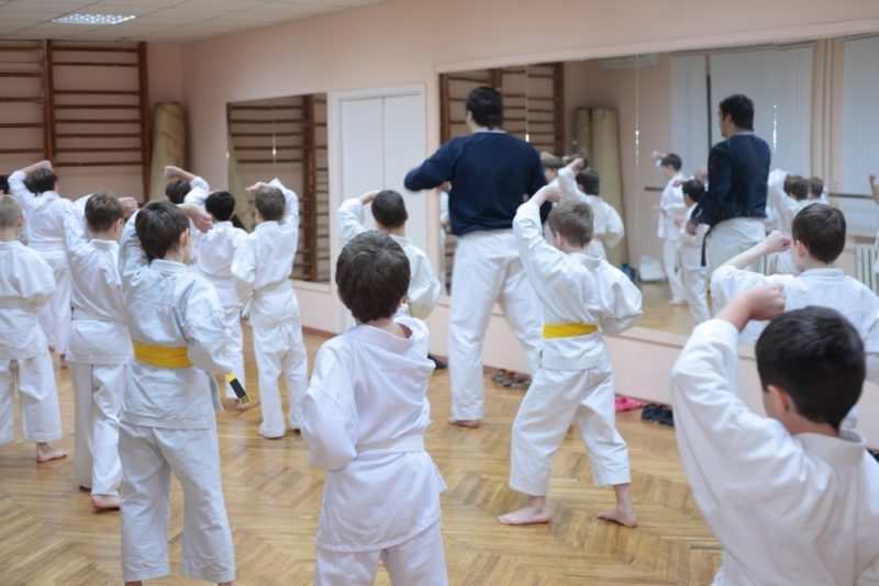 A room full of young martial artists follow the lead of their instructor.