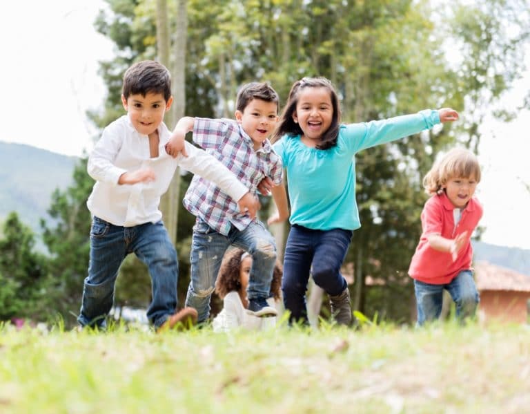 An energetic group of young children play excitedly outside.