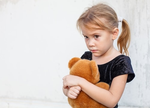 Nervous young girl hugs a stuffed animal.