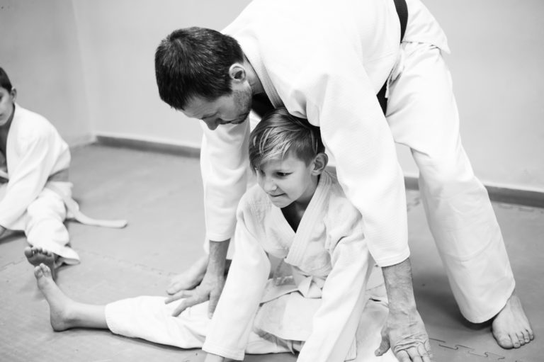 A black and white photo of a student training with a martial arts instructor