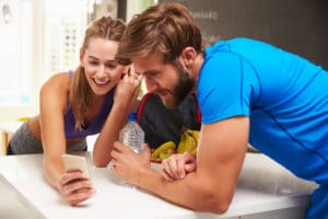 Couple Wearing Gym Clothing Reading Message On Mobile Phone about marketing your gym