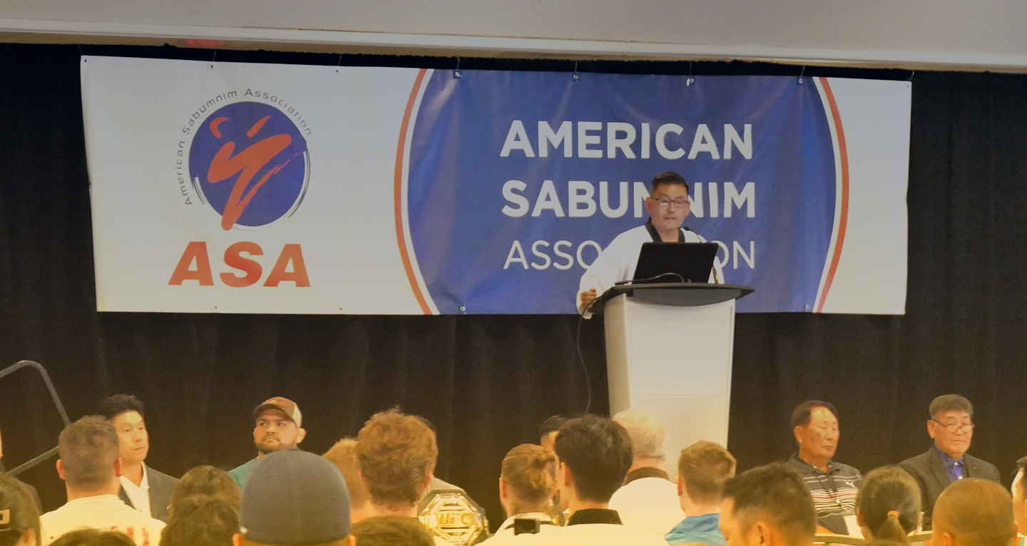 Man standing at podium in front of ASA banner speaking to crowd.