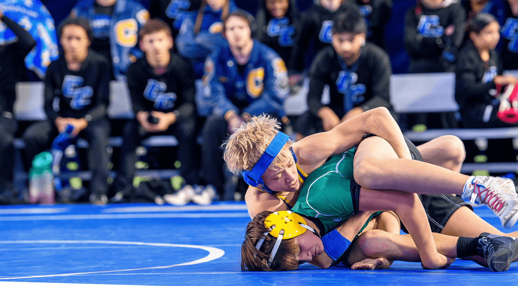 Two young wrestlers competing as onlookers watch