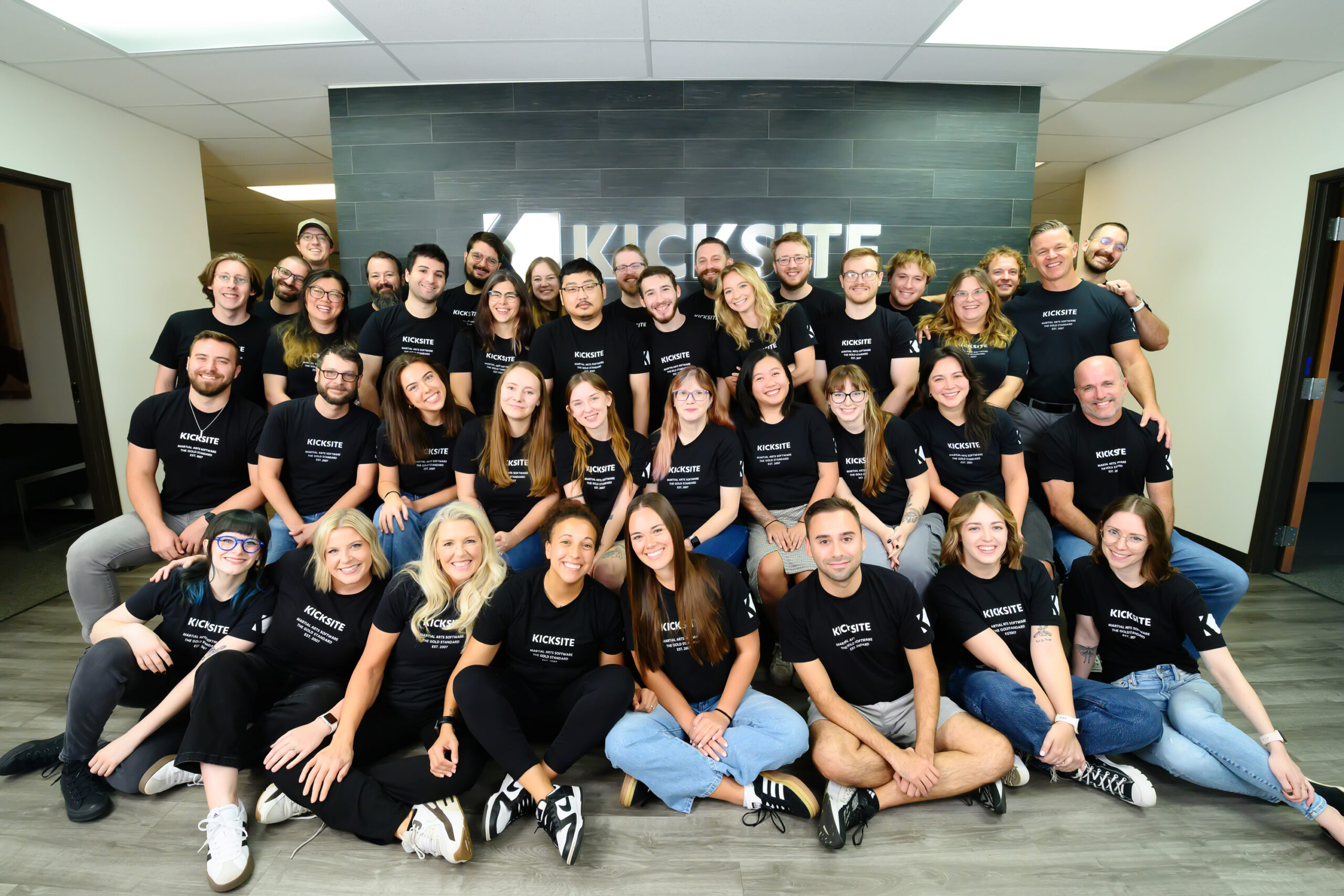 Group of Kicksite employees posing in front of Kicksite sign.